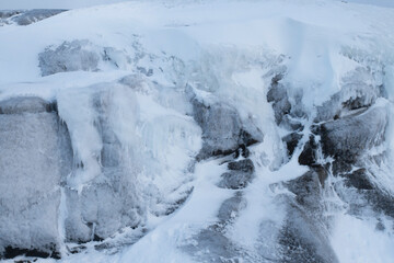 Beautiful winter landscape. Snow-covered icy blocks of stones close-up. rocks, icicles, ice, freezing. The harsh far north.
