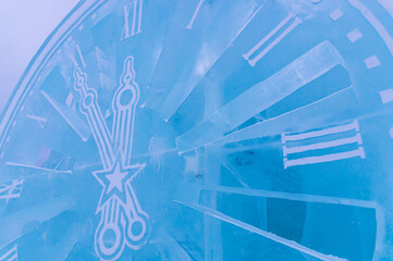 Celebrating the New Year in winter. Christmas and winter. A sculpture carved out of ice. Background of frozen ice decoration for Christmas. A watch made of ice. The dial of the ice clock.