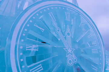 Celebrating the New Year in winter. Christmas and winter. A sculpture carved out of ice. Background of frozen ice decoration for Christmas. A watch made of ice. The dial of the ice clock.