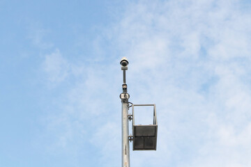 Closed-circuit CCTV, camera big size on pole in circle white blue sky background in sunlight. Tough...