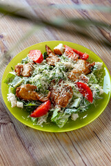 close-up view of delicious fresh caesar salad on plate on wooden table
