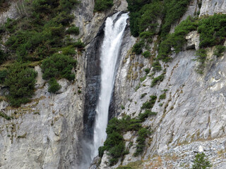Fototapeta na wymiar Schmuerfälle or Schmuer Waterfalls (Cascada da Pigniu oder Aua da Fluaz Wasserfälle) over the lake Panixersee (Lag da Pigniu), Pigniu-Panix - Canton of Grisons, Switzerland (Kanton Graubünden, Schweiz