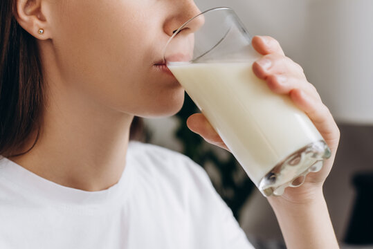 Cropped shot healthy young woman drinking milk with calcium for strong bone at home. Calm brunette girl holding soy milk on glass enjoy with nutrition wellness life. Natural milk fresh concept