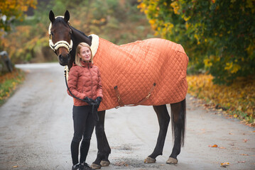 Autumn portrait of a girl and a horse. Beautiful auburn and orange colors.