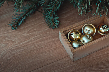 christmas golden balls in a wooden box. Christmas tree branches. The concept of a village Christmas. Background postcard. Wooden background. Horizontal image