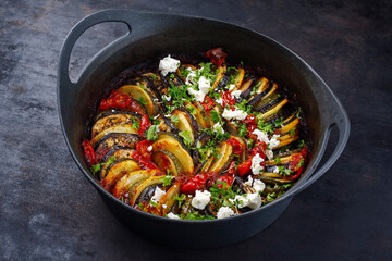 Modern style traditional Greek briam with sliced vegetable, potatoes and feta cheese served as...
