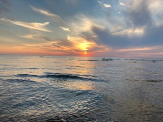 at the sea the red-golden sun shines out from behind the clouds before it sets