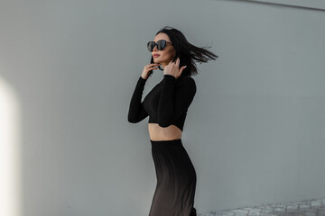 Cool fashion woman mode with trendy sunglasses in black fashionable clothes walks on the street...