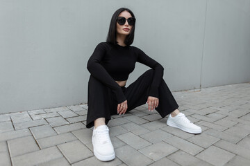 Beautiful woman with bob hairstyle with black fashion sunglasses in black sports stylish outfit...