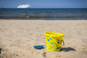 Children toys for relax or playing on sand at beach. Vacation time. Passengers ferry in background