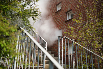 White smoke comes out of a window during a fire drill while the building is being ventilated