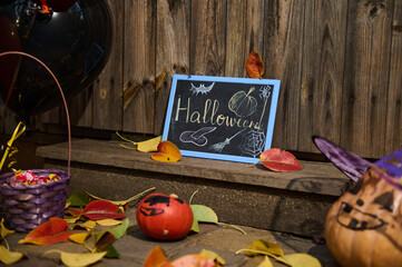 Halloween still life. Pumpkin in wizard hat, a purple basket with sweets ad candies next to a...