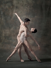 Young man and woman, ballet dancers performing isolated over dark green vintage background. Passion and support