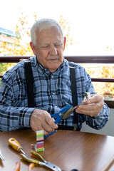 90 year old grandfather working at home, making oil lamps with his tools