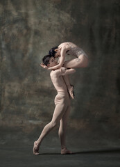 Young man and woman, ballet dancers performing isolated over dark green vintage background. Romantic look