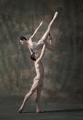 Young beautiful man and woman, ballet dancers performing isolated over dark green vintage background