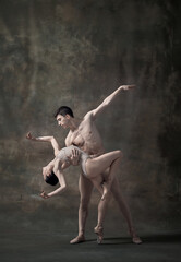 Young man and woman, ballet dancers performing isolated over dark green vintage background. Affection