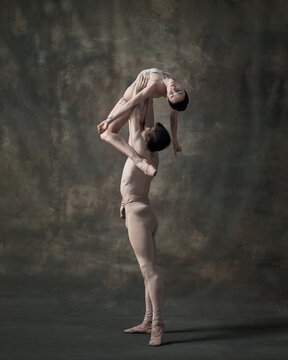 Young Man And Woman, Ballet Dancers Performing Isolated Over Dark Green Vintage Background. Holding High