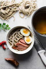 Homemade noodles, eggs and sausage in a white bowl, thick handmade noodles in broth