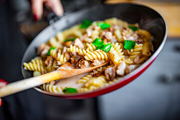 cooking tasty chicken fillet with mushroom in a creamy sauce with fusilli pasta in pan on kitchen