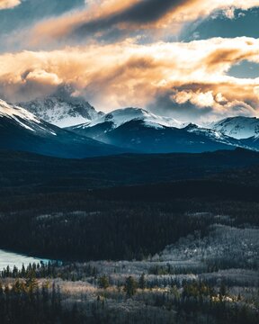 Vertical distant view of mountain range covered in snow on a cloudy day in Canada
