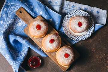 Sufganiyot jelly doughnuts cooked in oil on wooden table background. Traditional Jewish festive food dessert for Hanukkah holiday. Flat lay, top view.