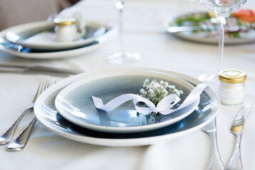 beautiful table setting with white flowers, ribbon and cutlery at home or in a restaurant