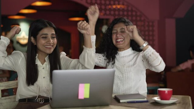favorite Indian two women cricket match on laptop by using internet online. young Asian group of business women people fun and exciting with the game of cricket match wining,at the coffee shop.