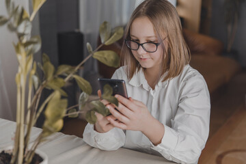 Teenage girl at home vlogging, uses mobile phone to surf the internet or chat with friends