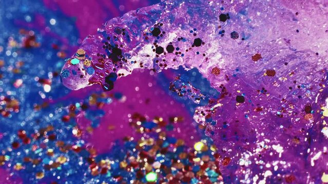 Fluid magic. Glittering flow art. Festive background. Transparent shimmering stream of liquid paint with colorful tinsels floating in macro shooting.