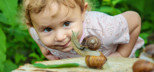 The child examines the snails on the tree. Selective focus. © yanadjan