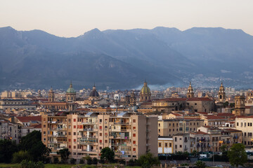 Residential Homes and Historic Church Buildings with mountains in background in Palermo, Sicily, Italy. Sunrise Sky.