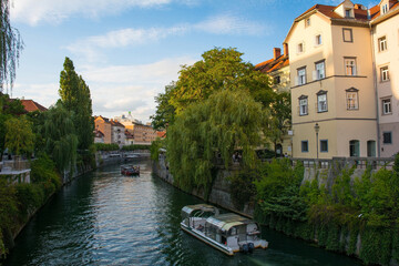Tourist boats pass along the Ljubljanici River in central Ljubljana, Slovenia. The Fishmarket...