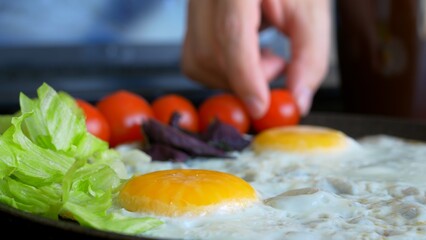 For breakfast, delicious scrambled eggs with vegetables and fresh tomatoes. With a fork, take a piece of scrambled eggs and green beans. Breakfast on a keto diet is rich in fats and proteins.