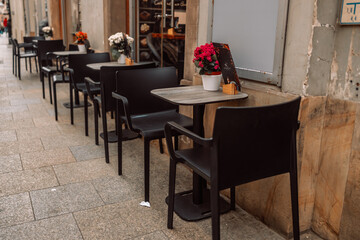Street view. Cozy street cafe with black chairs and potted flowers on the table during the morning. Krakow, Poland, Europe