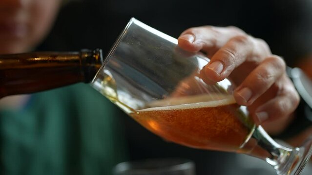 Closeup hand serving beer into glass. Man pouring alcoholic beverage. fresh cold alcohol drink. Pale ale