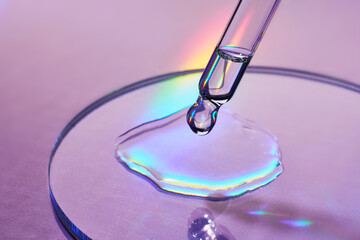 Pipette with sample of cosmetic product in petri dish on holographic background, iridescent...