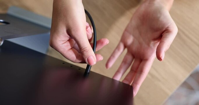 Hands insert a plug into a black screen, a close-up