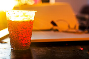 energy drink in a plastic transparent cup against the sun. Horizontal.