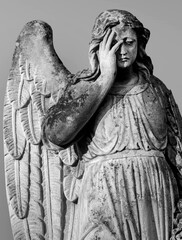 An ancient sculpture of a sad angel mourning the dead.