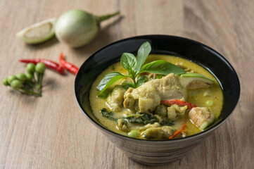 Traditional Thai food with chicken green curry on a wood table with side dishes.