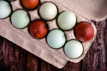 Blue, Green, and Brown Heritage Eggs In an Egg Carton On a Rustic Wood Background: Multicolored eggs in a paper egg carton on a wooden table