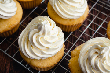 Homemade Vanilla Cupcakes on Wire Cooking Racks: Overhead view of vanilla cupcakes with vanilla buttercream frosting