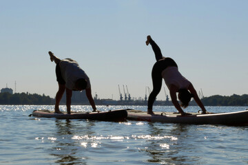 Two people doing paddle board yoga in the river