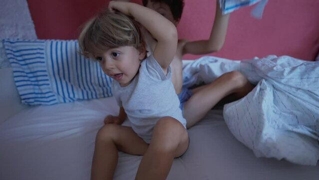 Happy children in morning bed. Cute little boy getting up from bedsheets. Two brothers hanging out