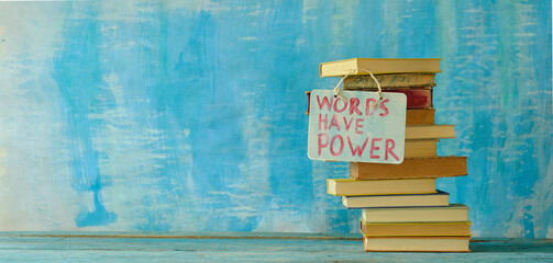 Stack of hardback books with words have power sign on blue...