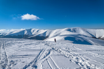 Snow covered hills with tracks of skiers and snowboarders. Winter mountains landscape of Carpathians.