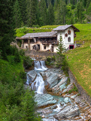 Fototapeta na wymiar Sappada, Italy - July 27, 2022: Idyllic abandoned water mill in Sappada, an alpine village on the edge of the Italian Dolomites