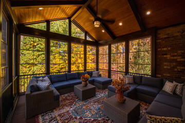 Cozy screened porch enclosure with contemporary furniture at Thanksgiving Holiday. Flower bouquet...