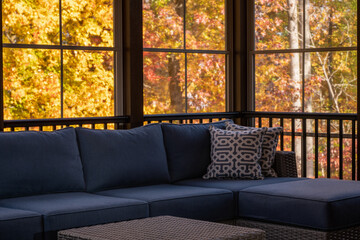 Cozy screened porch enclosure view in autumn. Fall leaves and woods in the background.